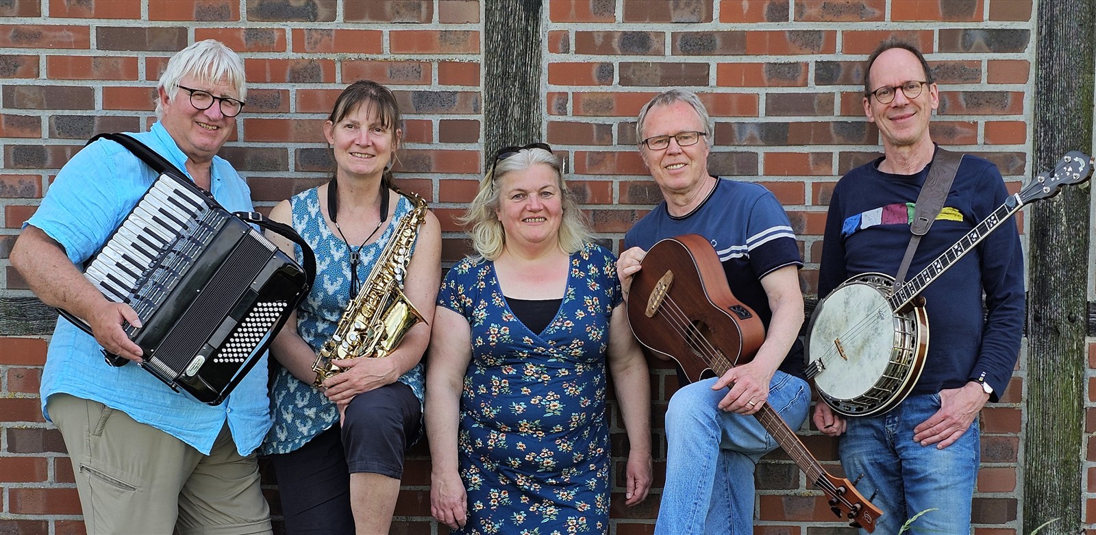 Die Weltmusik-Band Schallermanns aus Münster mit Akkordeon, Saxophon, Ukulele-Bass und Banjo vor einer Backsteinwand