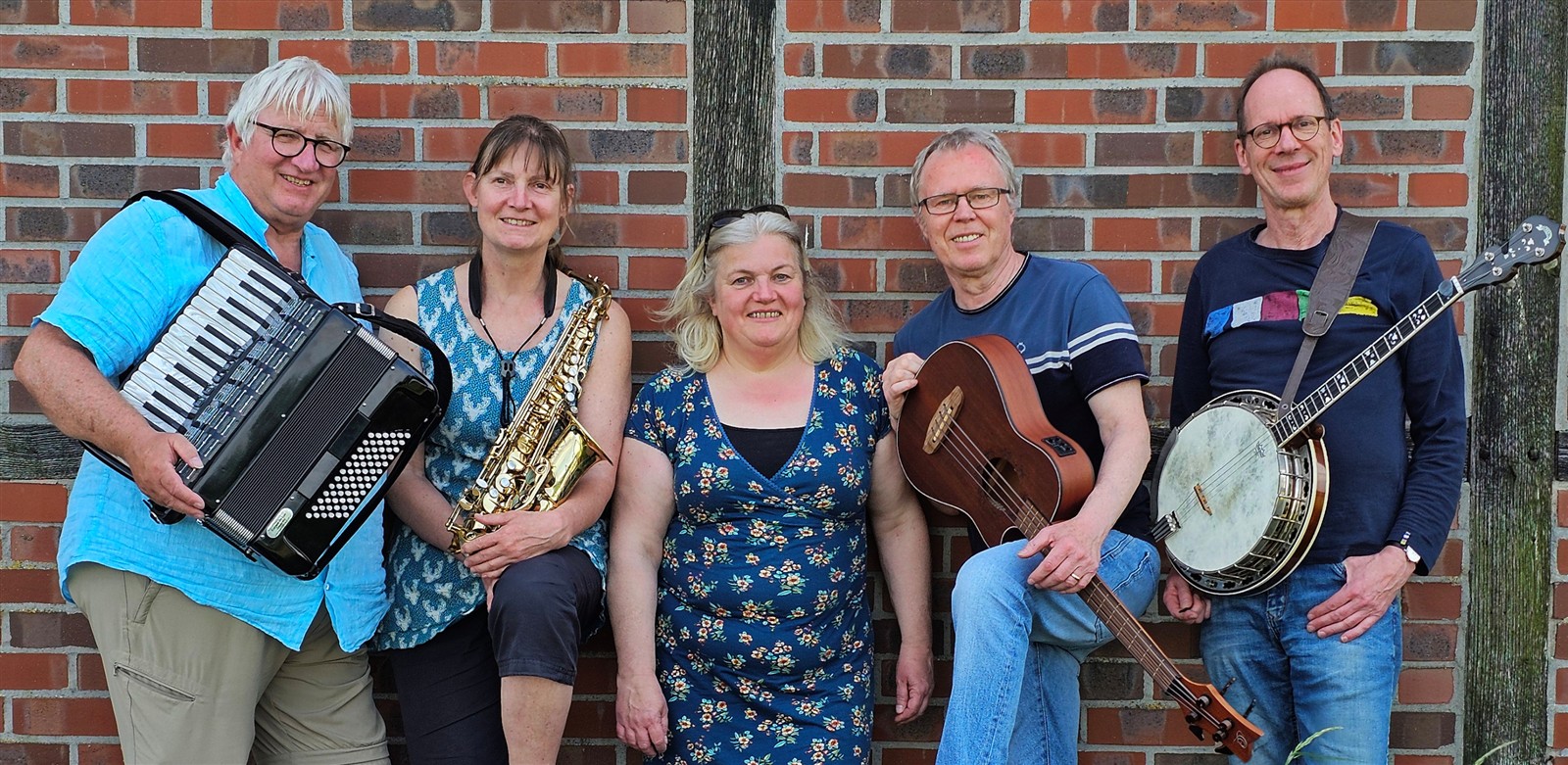 Die fünf Mitglieder der Weltmusik-Band Schallermanns aus Münster vor einer Backsteinwand